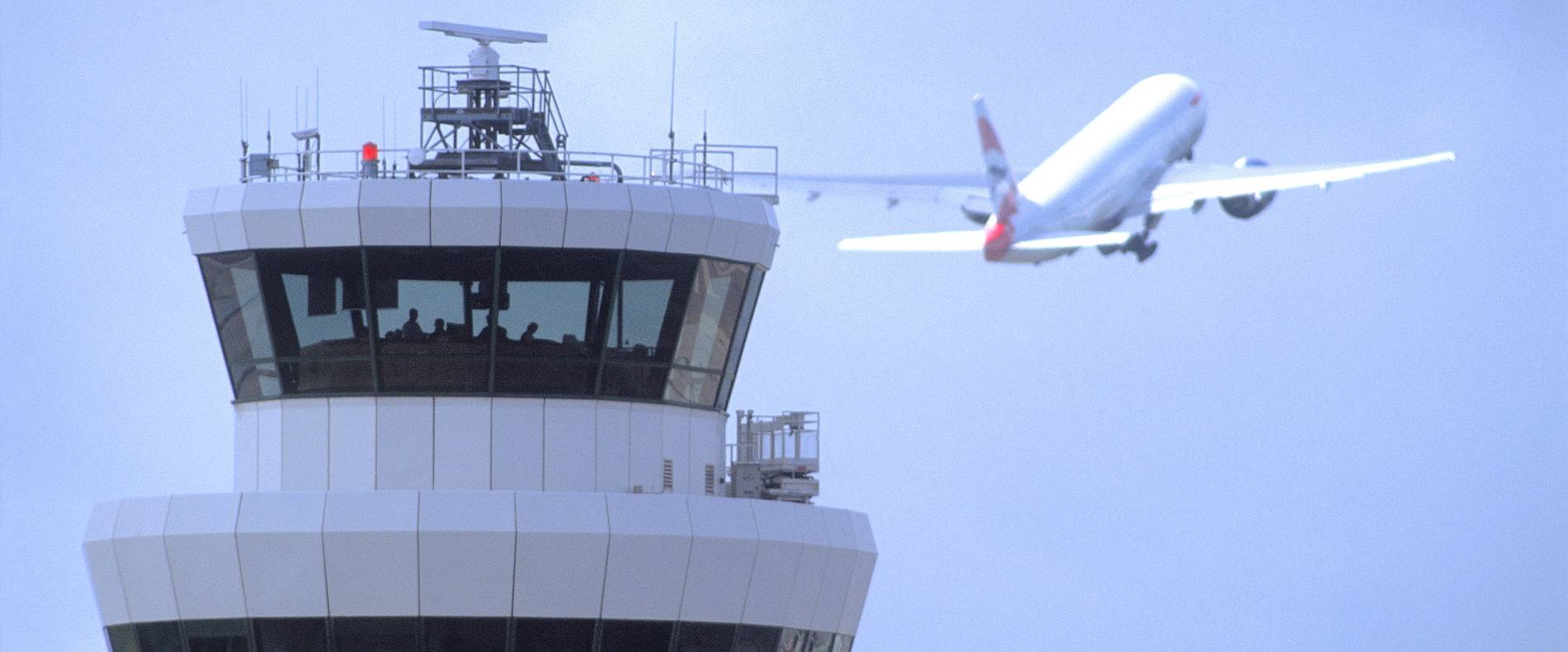 Bild des Towers in London Gatwick mit einem aufsteigenden Flugzeug dahinter